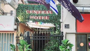 The entrance of Central Hotel with a gated entrance, potted plants, and flags. - Central Hotel (Tel Aviv)