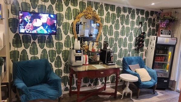 Ein Zimmer mit einem großen Fernseher, einer Kaffeemaschine, einem Spiegel und einem Kühlschrank.