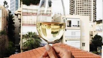 A hand holding a wine glass with a cityscape in the background.