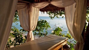 A bed with a view of the sea, draped with white curtains, and surrounded by greenery. - Easy Diving and Beach Resort (Sipalay)