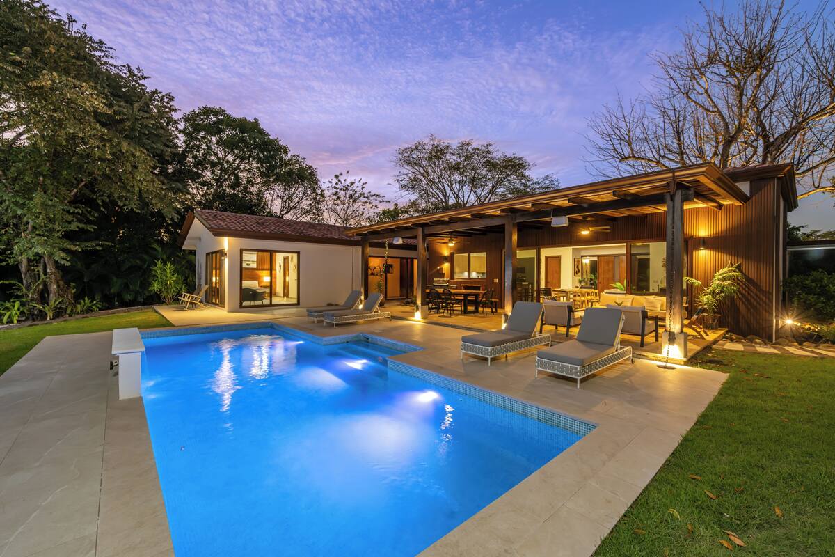 A modern house with a swimming pool, outdoor seating, and a patio area.