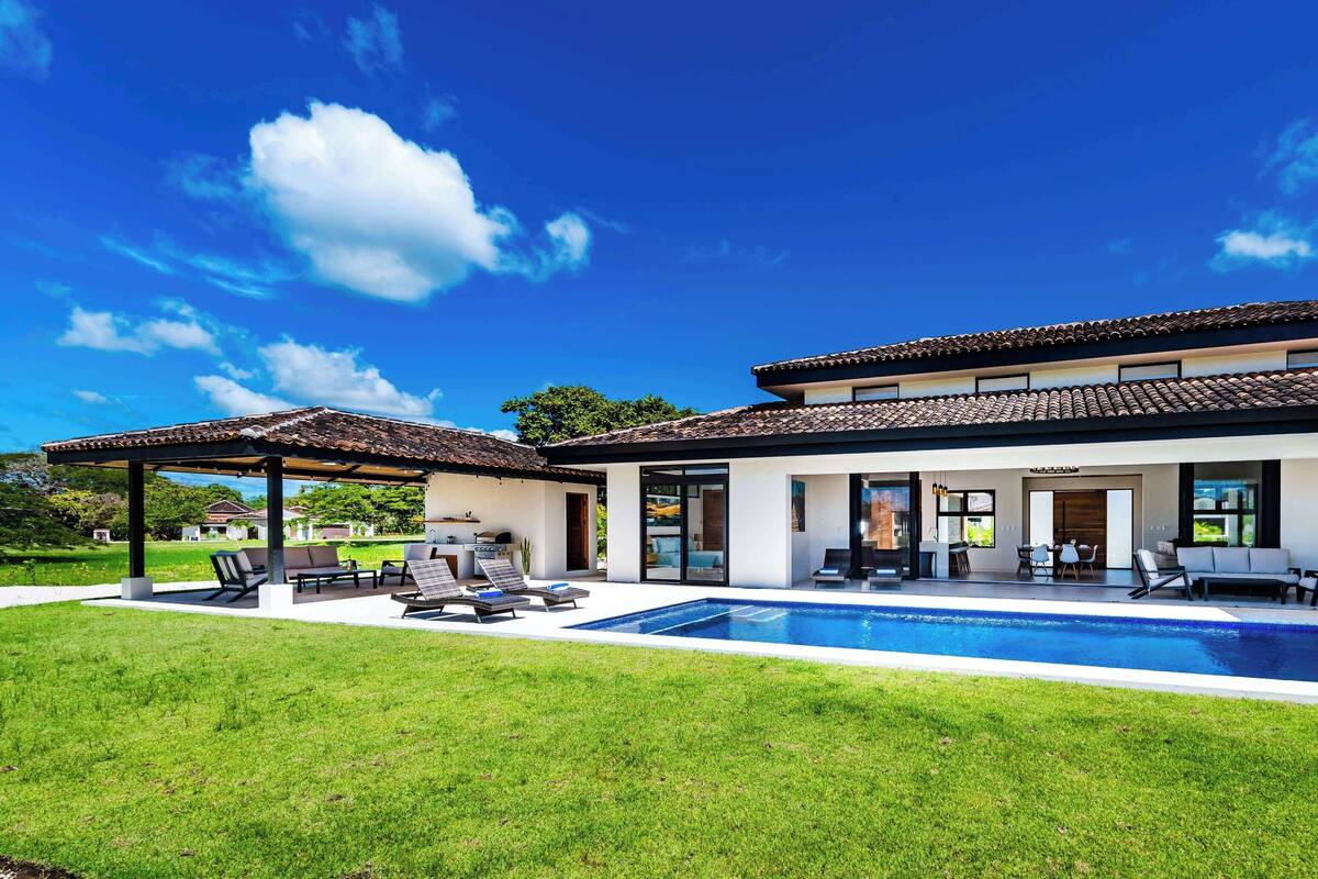 A modern house with a swimming pool, outdoor seating, and a covered patio.