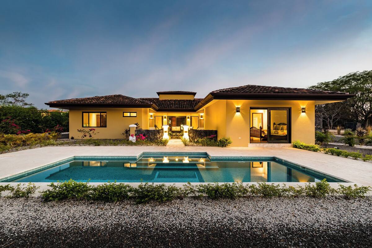 A two-story house with a swimming pool, a patio, and a well-maintained garden.