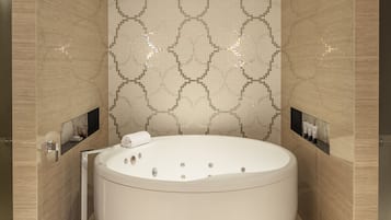 Un baño moderno con una bañera independiente grande, paredes con azulejos y estantes empotrados.