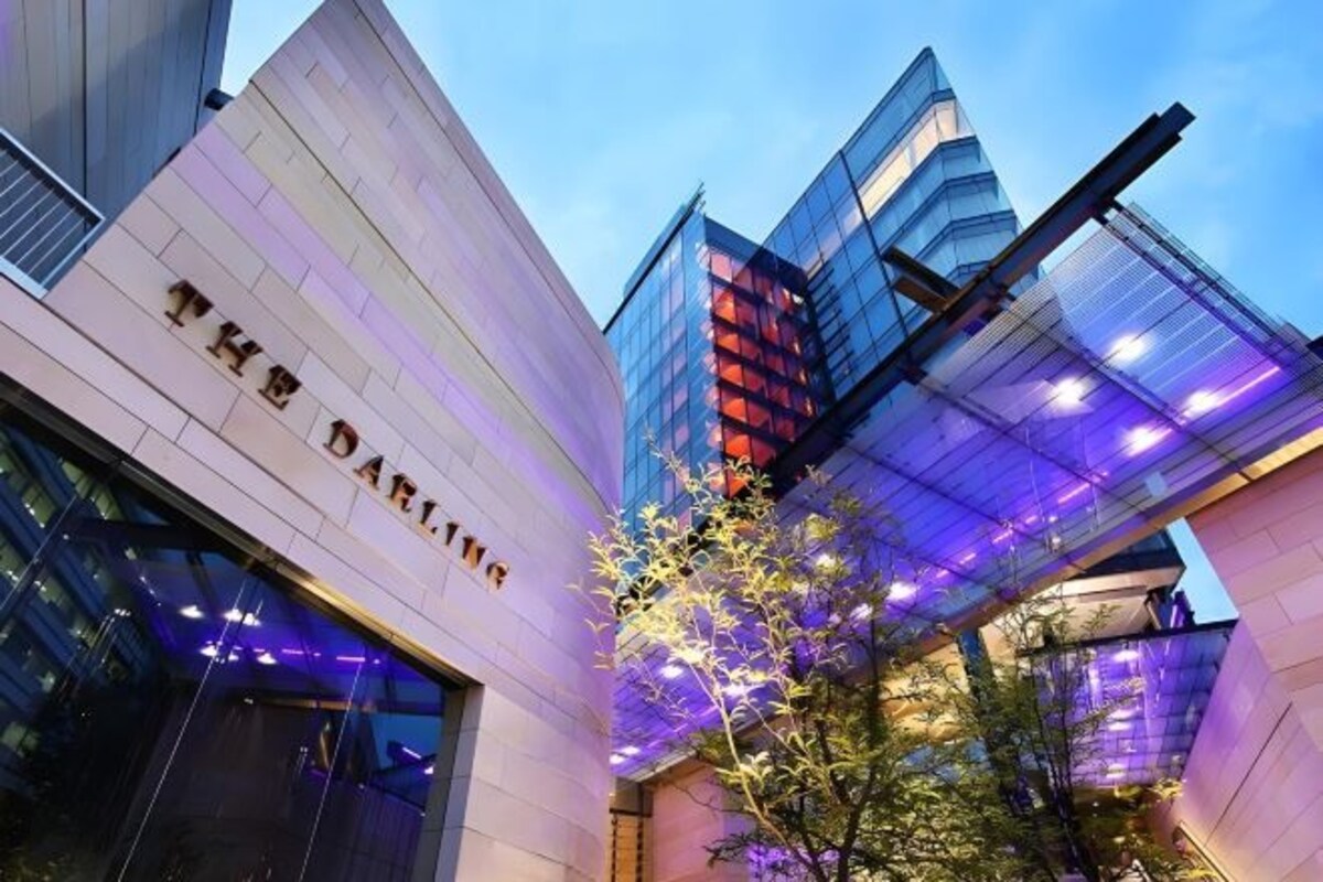 A modern building with 'THE DARLING' signage, glass facade, and illuminated structure.