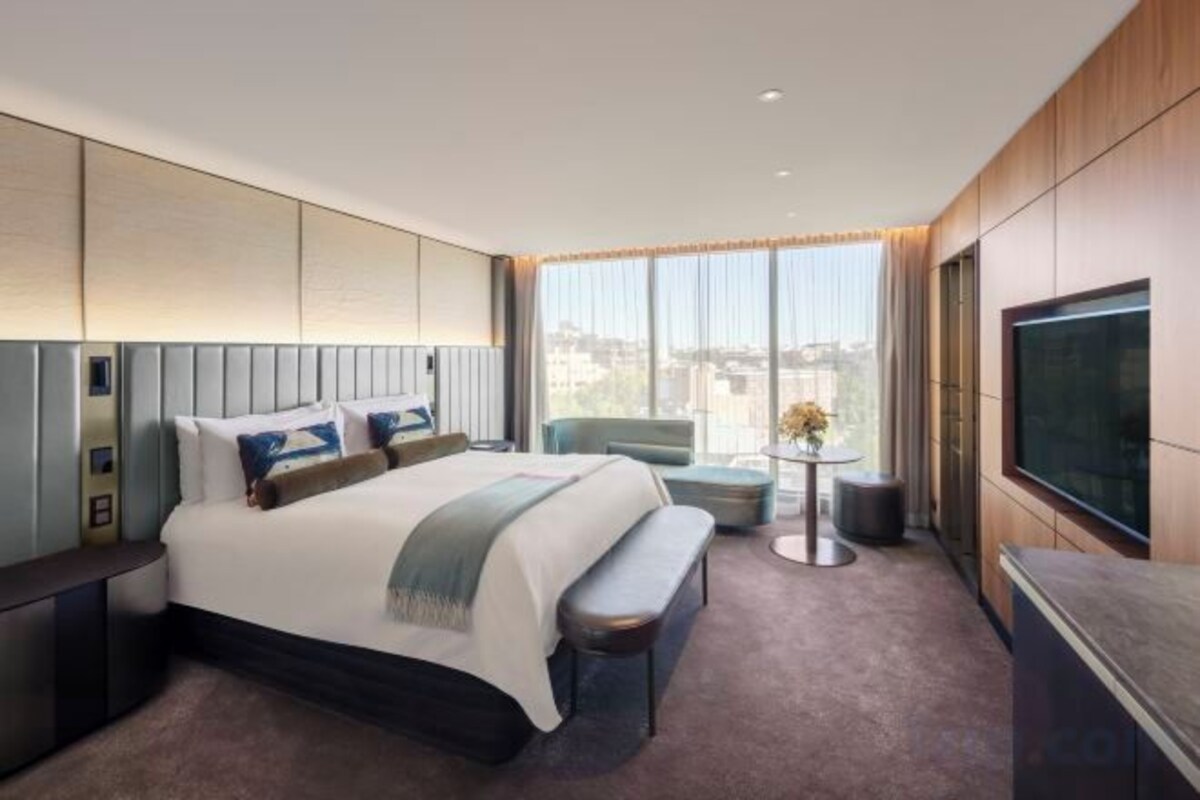 Habitación de hotel moderna con una cama grande, televisión de pantalla plana, una pequeña zona de estar y vistas a la ciudad.