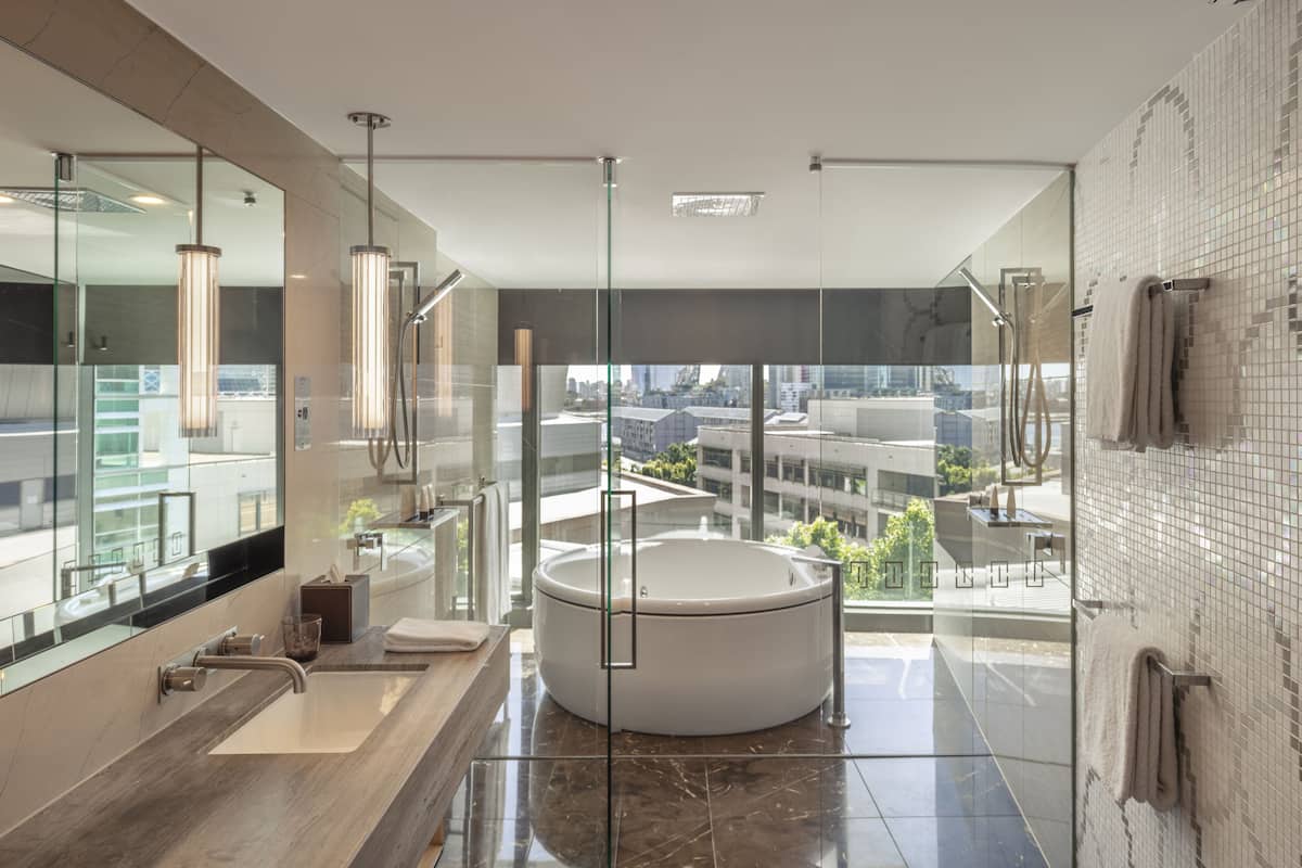 Un baño moderno con una bañera grande, una ducha con cerramiento de vidrio y vistas a la ciudad.