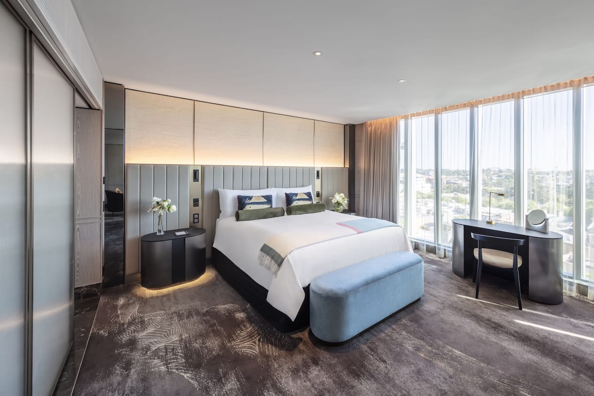 Una habitación de hotel moderna con una cama grande, un escritorio y vistas a la ciudad.
