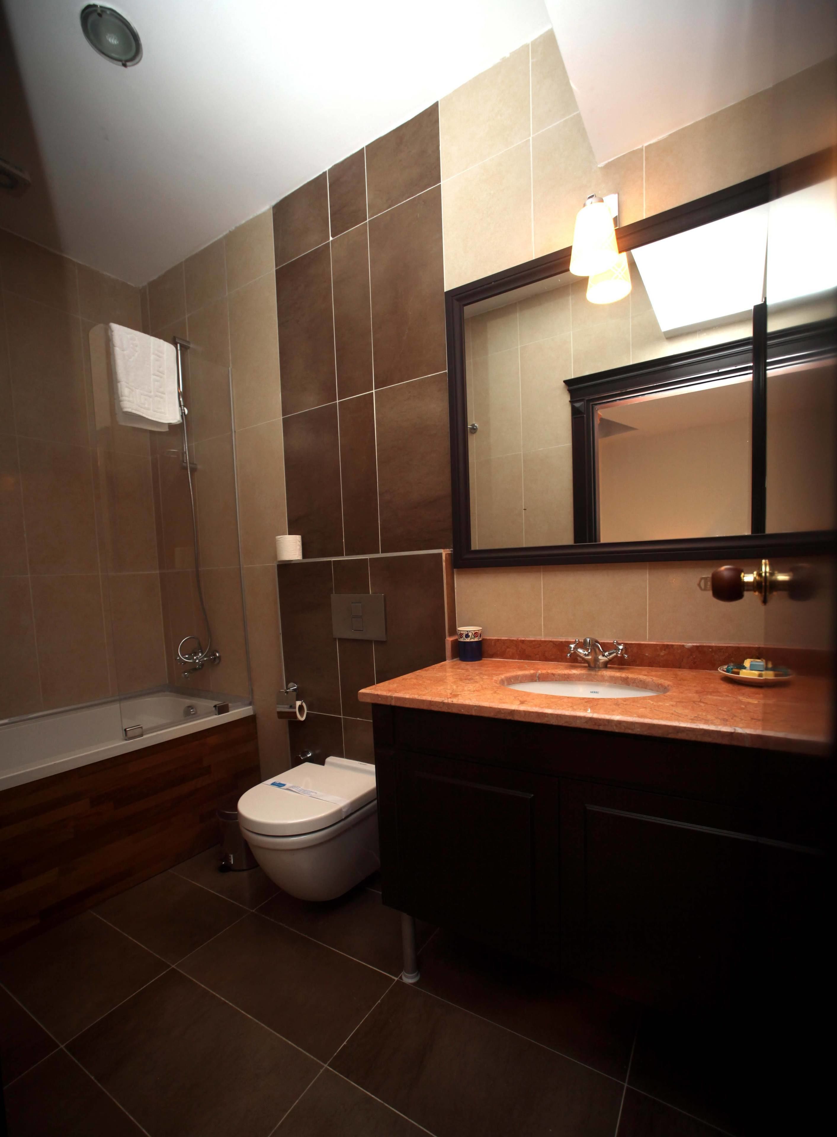 A bathroom with a bathtub, toilet, sink, and a large mirror.