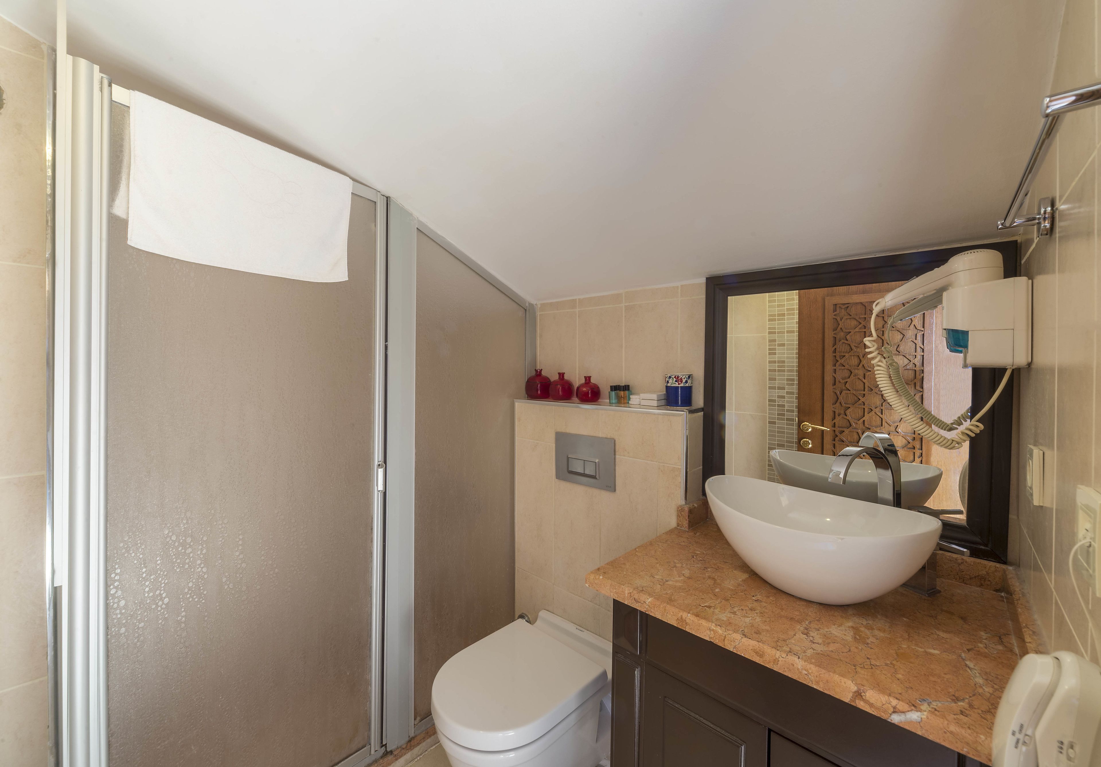 A bathroom with a white toilet, a large white sink, and a shower area.