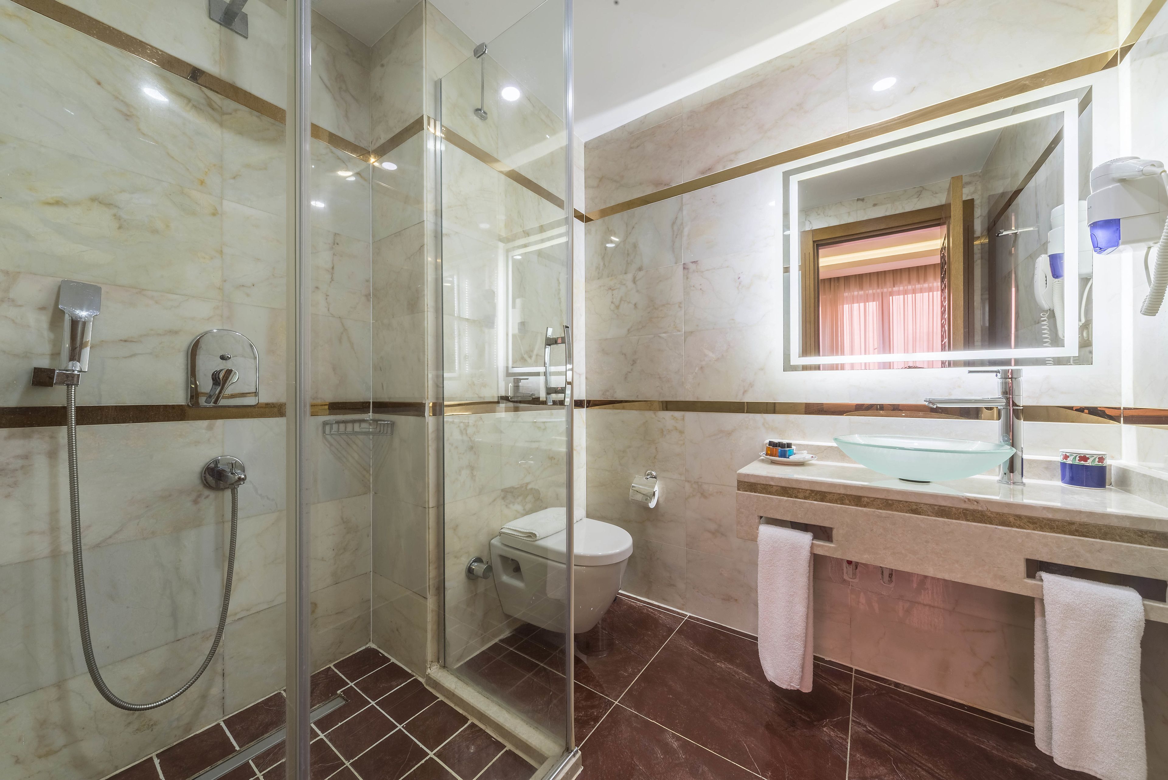 Een moderne badkamer met een douchecabine, een toilet, een wastafel met spiegel en een haardroger aan de muur.