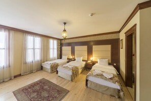 A hotel room with three beds, a wooden floor, a large rug, and a chandelier. - Lalinn Hotel (Istanbul)