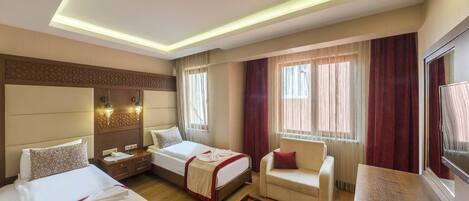 A hotel room with two beds, a sofa, a desk, and a large window with curtains.