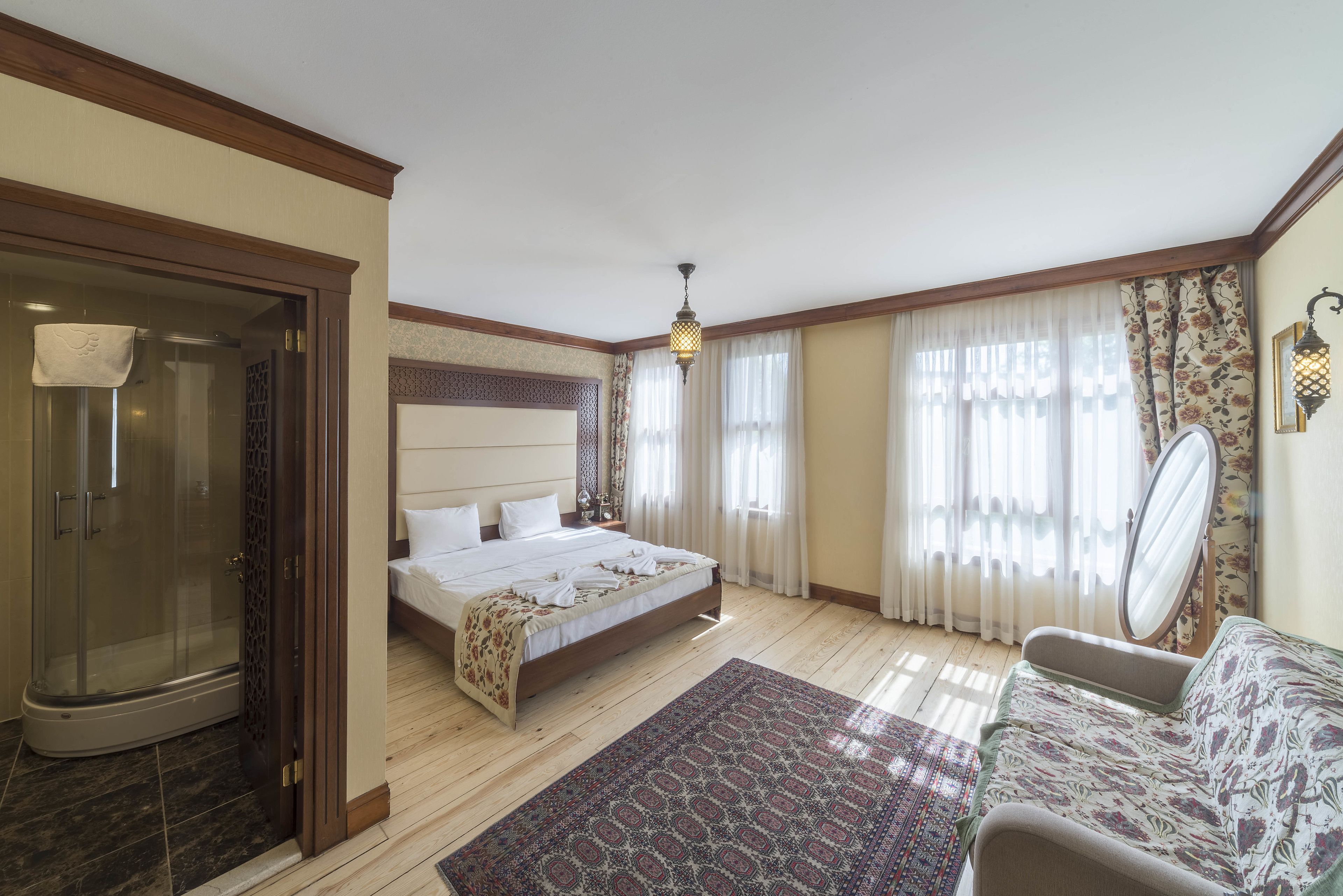 A bedroom with a bed, a shower, a sofa, and a patterned rug.