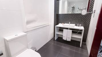 Un bany modern amb un vàter blanc, un lavabo amb mirall i una tovallola penjada a la paret.