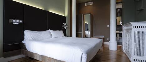 Un dormitorio moderno con una cama grande, suelo de madera y un espejo amplio.