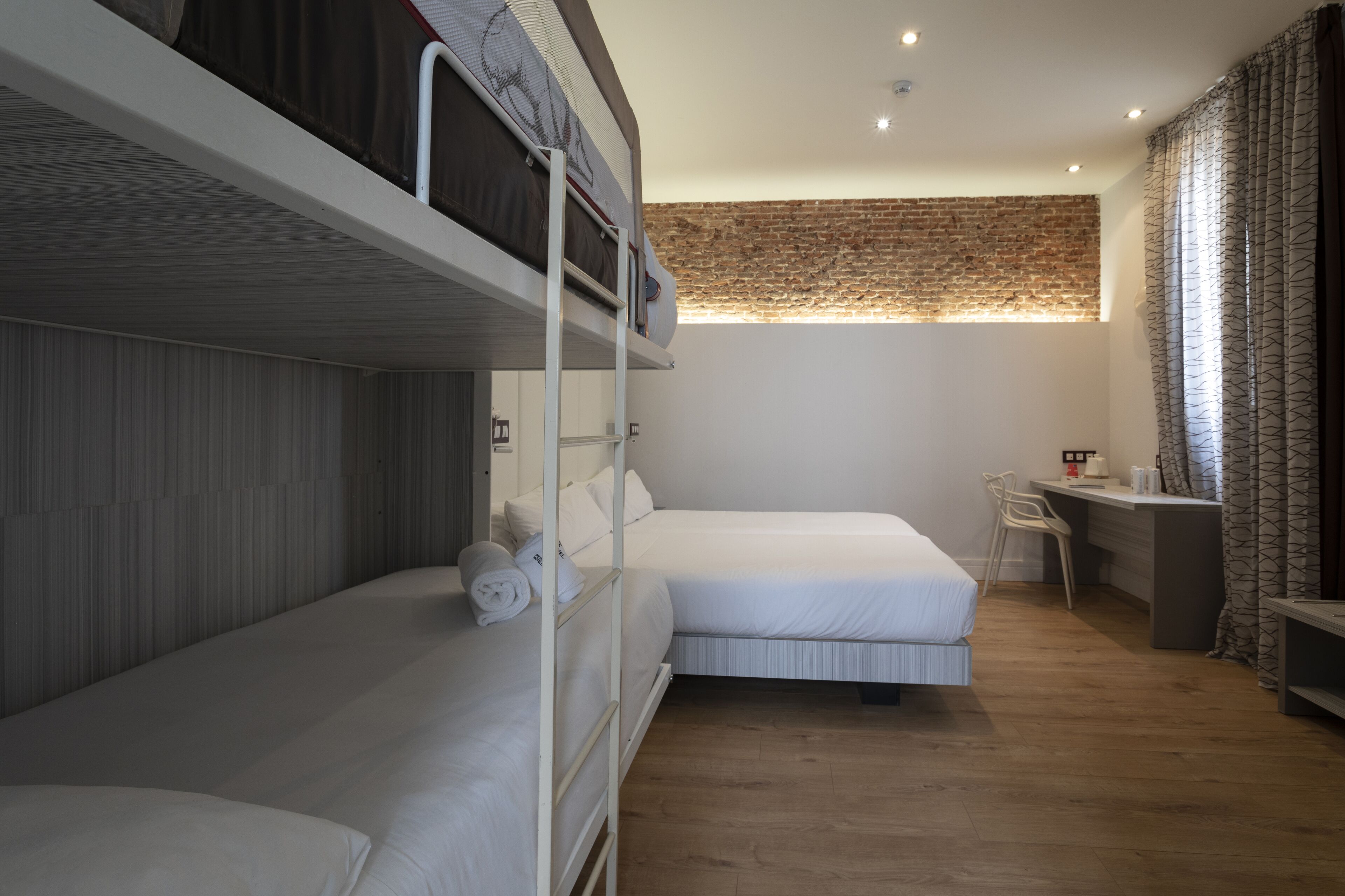 A room with bunk beds, a desk, and a chair.