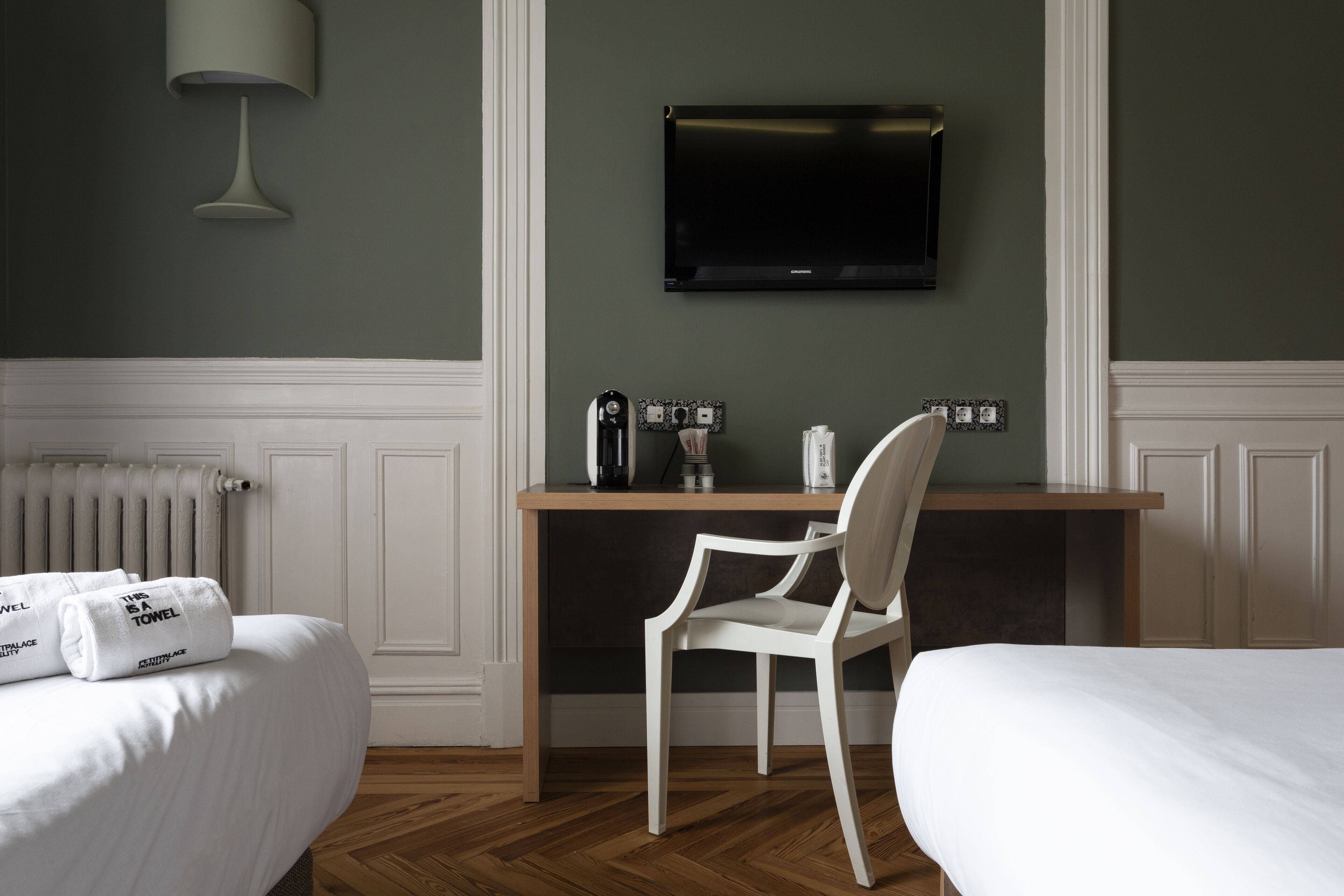 Ein Hotelzimmer mit einem Bett, einem Schreibtisch mit Stuhl, einem Fernseher und einer Heizung.
