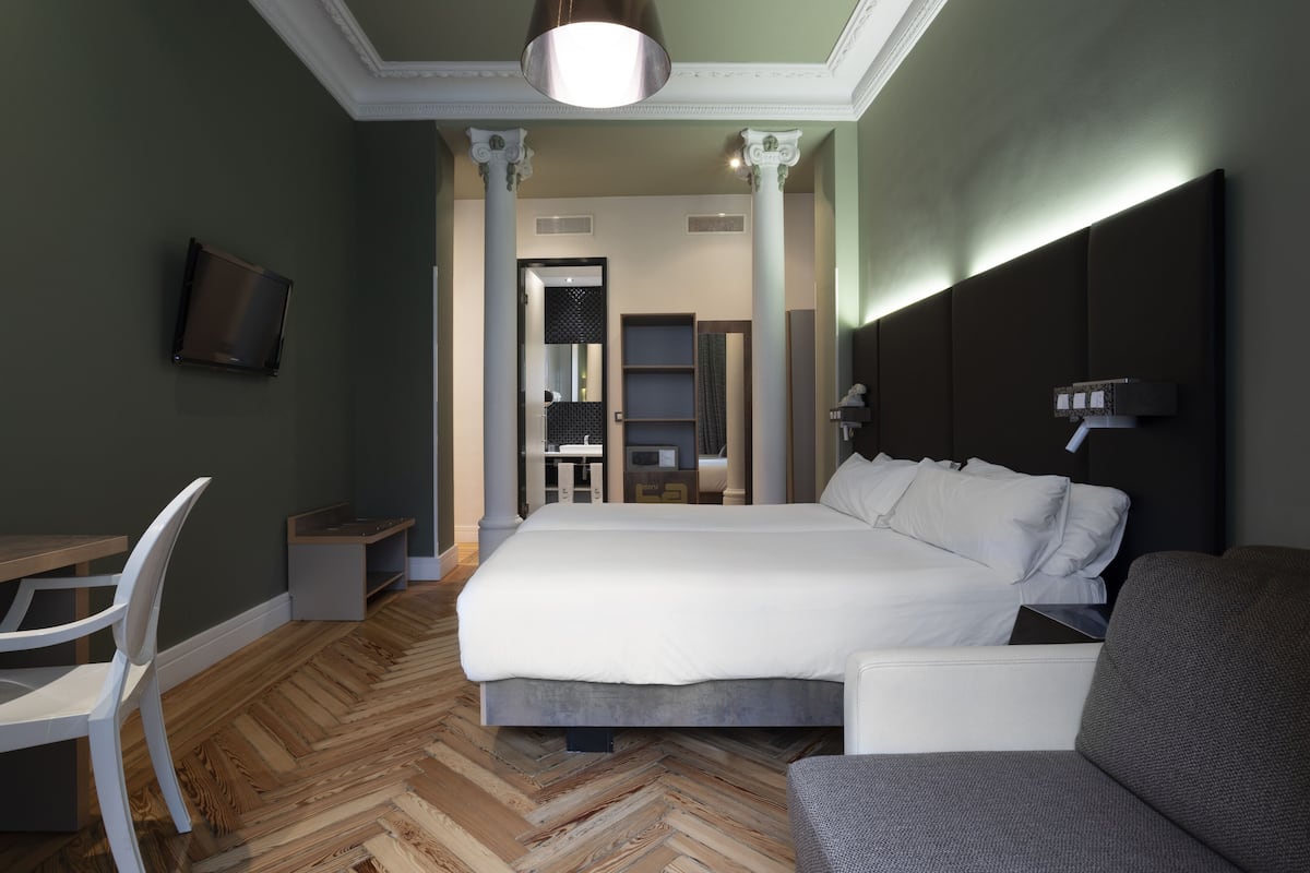 Una habitación de hotel moderna con una cama grande, un escritorio, una silla y un sofá.
