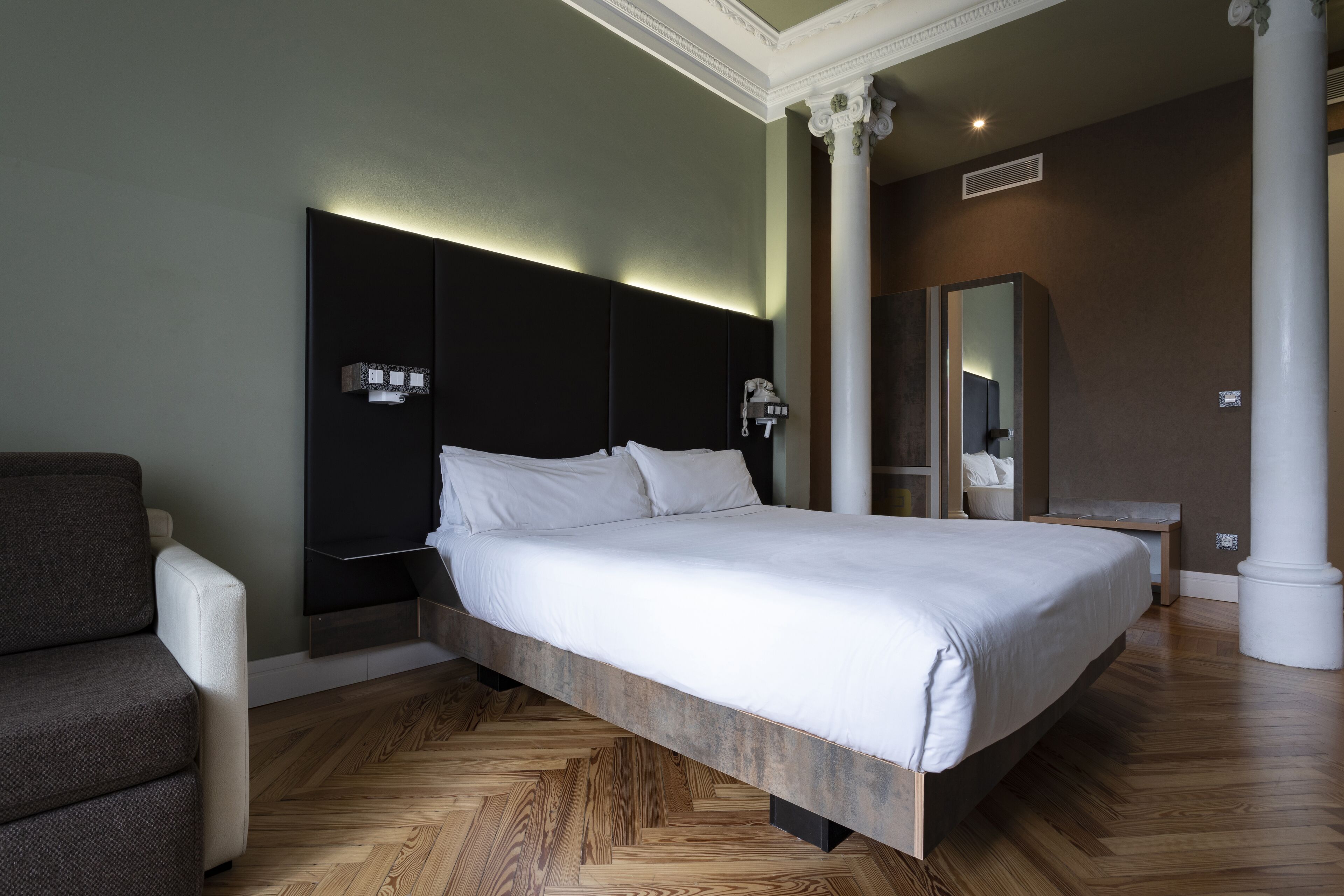 Un dormitorio moderno con una cama grande, una mesita de noche, una silla y un espejo.