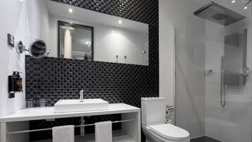 A modern bathroom with a white sink, toilet, and glass-enclosed shower.