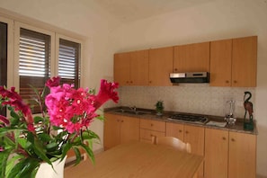 Una cucina con pensili in legno, una cappa aspirante in acciaio inossidabile, un lavello e un tavolo da pranzo.
