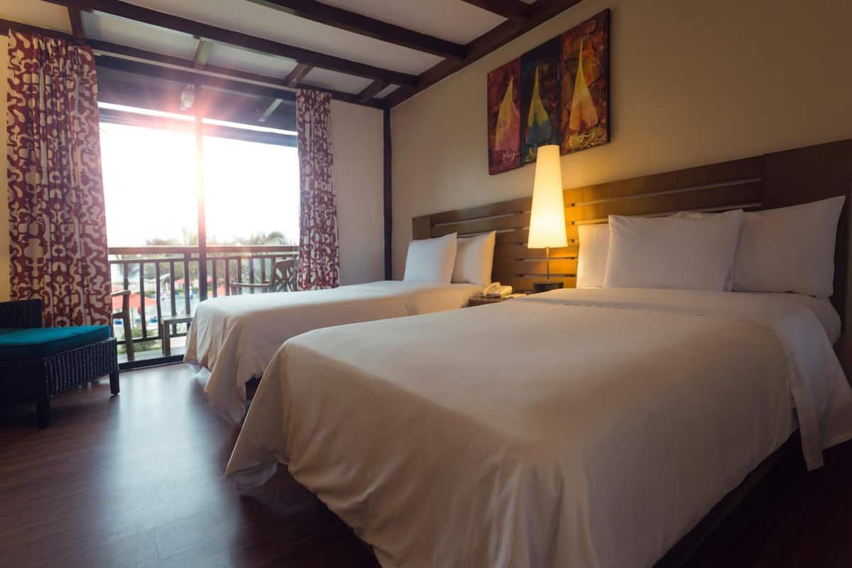 Quarto de hotel com duas camas, varanda com vista e um quadro na parede.
