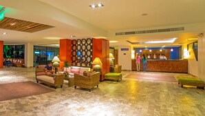 A lobby with wicker furniture, a reception desk, and a patterned wall. - Royal Decameron Punta Centinela (Santa Elena)