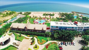 Un resort con piscina, playa y un edificio grande de varios pisos.