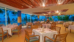 A restaurant with tables set for dining, large windows, and a view of the ocean. - Royal Decameron Punta Centinela (Santa Elena)