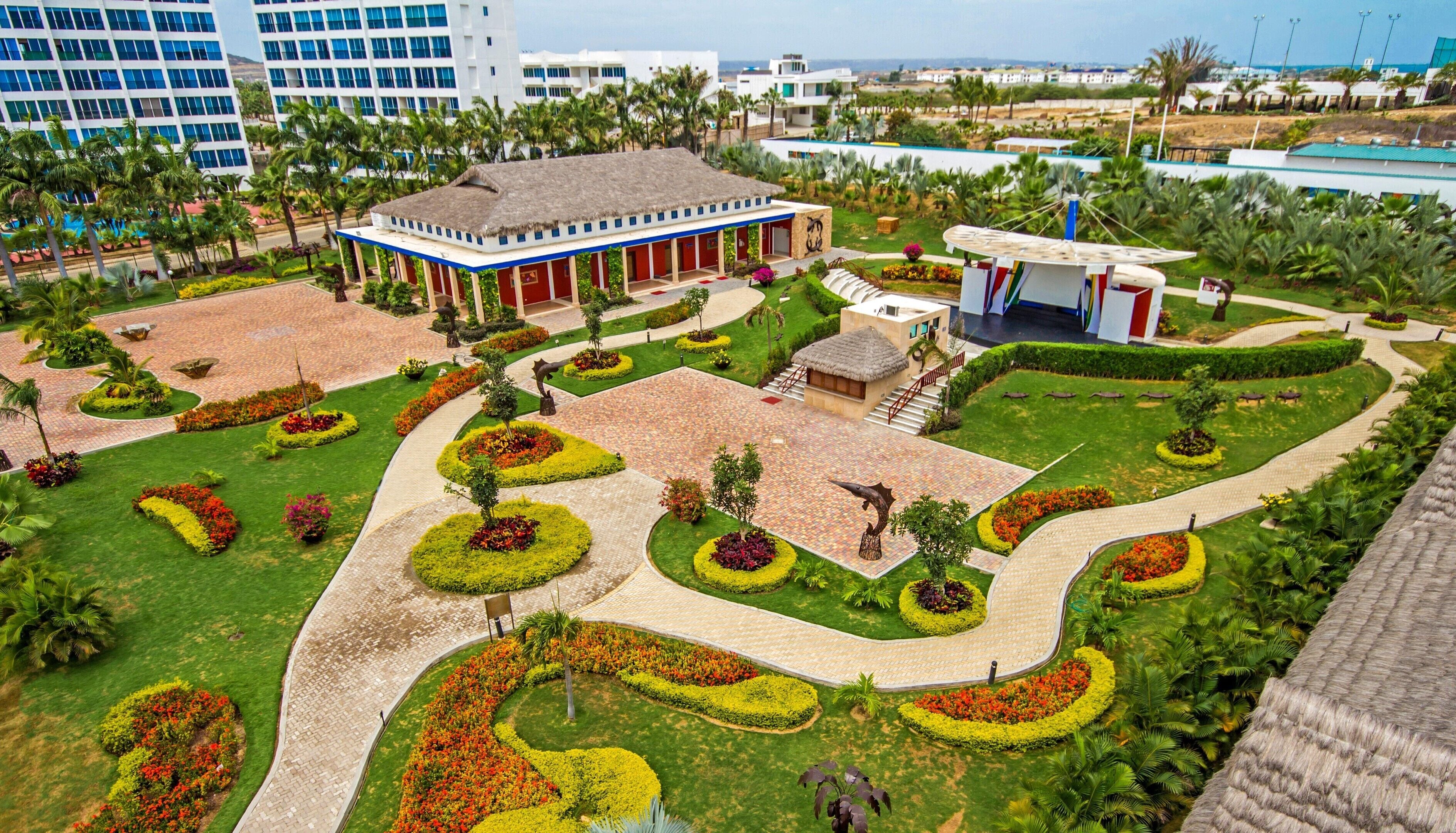 A hotel with a central courtyard, surrounded by lush gardens and palm trees.