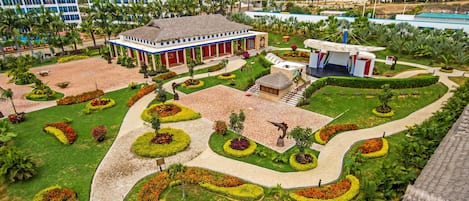 A hotel with a central courtyard, surrounded by lush gardens and palm trees.