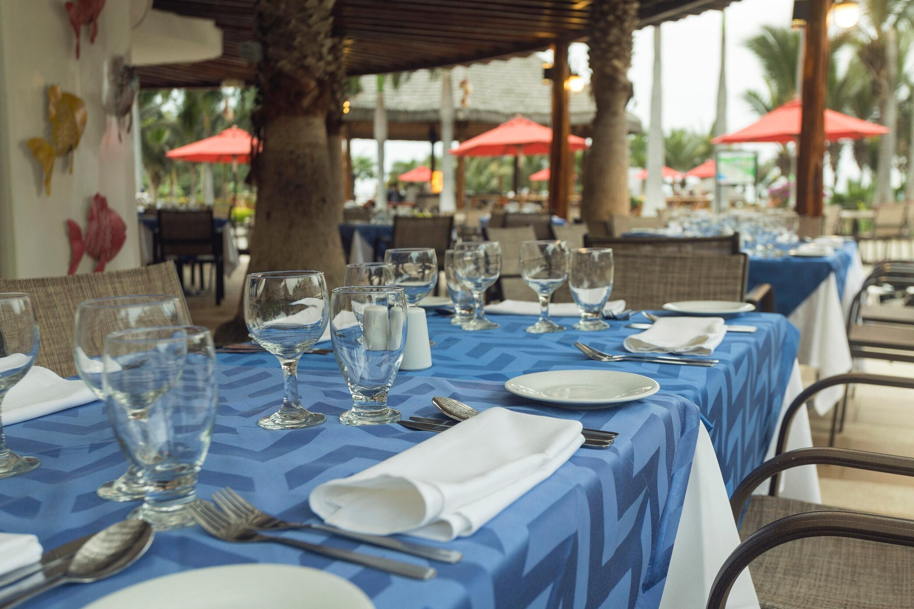 Een gedekte restauranttafel met een blauwe tafelkleed, witte servetten en glazen.