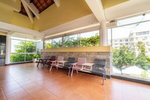 A spacious indoor area with large windows, a stone wall, and several wooden chairs and tables. - Thai Hoa Resort (Phan Thiet)