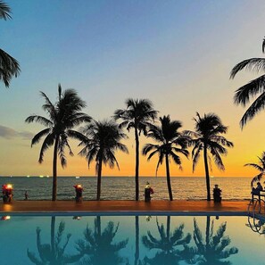 A poolside view with palm trees and a sunset over the ocean. - Thai Hoa Resort (Phan Thiet)