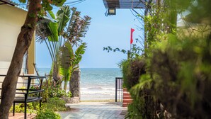 A pathway leading to a beach with a flag, palm trees, and a view of the ocean. - Thai Hoa Resort (Mui Ne)