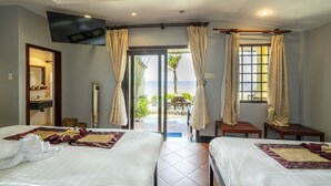 A hotel room with two beds, a TV, a balcony with curtains, and a view of the sea. - Thai Hoa Resort (Mui Ne)
