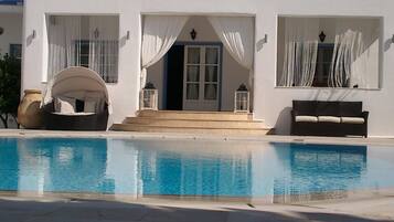 Enjoy a refreshing dip in the pool surrounded by a clean, white building with a covered seating area.