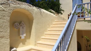 A staircase with a stone wall and a blue railing. - Anatolia Hotel (Mykonos)