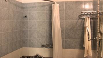 Un baño con ducha, lavabo y toallero.