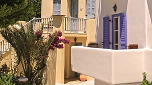 A traditional Mediterranean-style building with a balcony, white walls, and blue shutters. - Anatolia Hotel (Mykonos)