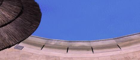 A curved architectural structure with a clear blue sky above.