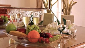 A table with a fruit platter and a mirror reflecting the room's ceiling and wall. - Anatolia Hotel (Mykonos)