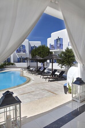 Una piscina al aire libre, sombrillas, sillones reclinables de piscina