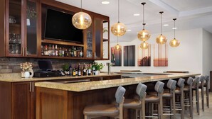 Een moderne keuken met een bar, houten kastjes en barstoelen.