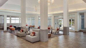 Een ruime lobby met hoge plafonds, grote ramen en moderne zithoekjes.