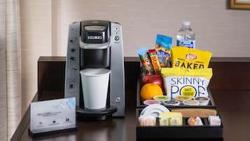 Een koffiezetapparaat, een dienblad met snacks en een welkomstbord op een hotelbalie.