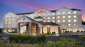 Een Garden Inn hotel met een moderne gevel, een overdekte ingang en een aangelegde voortuin.