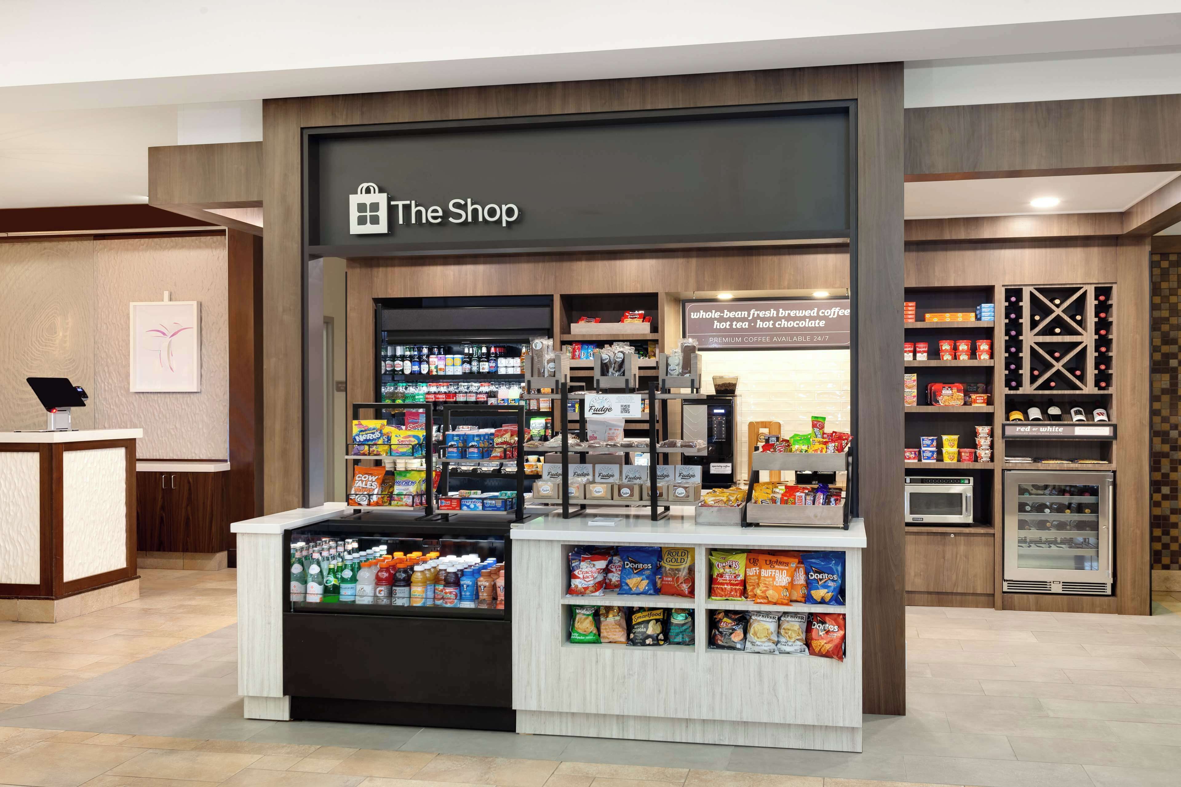 Una tienda llamada 'The Shop' con una variedad de aperitivos, bebidas y una máquina de café.