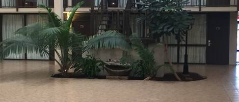 Un vestíbulo amplio con una escalera central, varios balcones y plantas de interior.